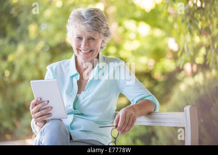 Donna anziana con tavoletta digitale all'aperto Foto Stock