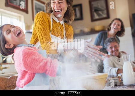 Madre e figlia giocando con la farina in cucina Foto Stock