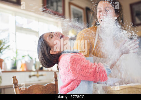 Madre e figlia giocando con la farina in cucina Foto Stock