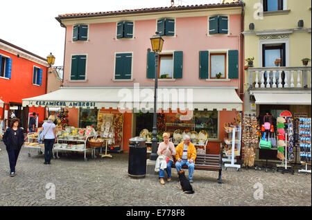 Caorle, Veneto, Italia . Maggio 2014, Eldery giovane si siede al banco a Caorle città vecchia. Foto Stock