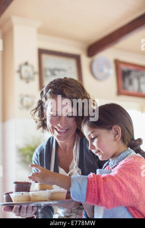 Nonna e nipote immissione tortine sul vassoio Foto Stock