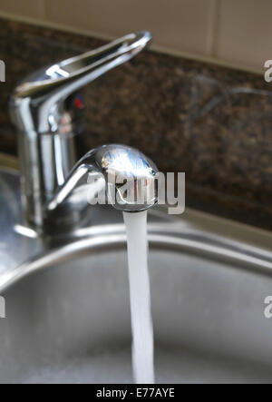 L'acqua che scorre dal rubinetto nel lavello da cucina Foto Stock