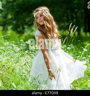 Carina ragazza con abito bianco in campo verde. Foto Stock