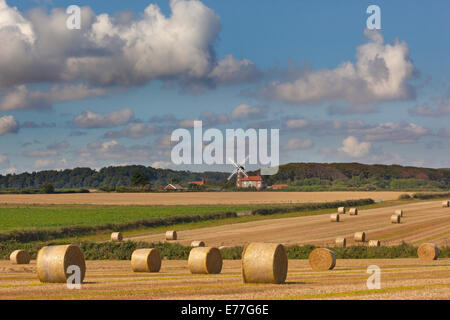 Paesaggio di raccolto con le balle di paglia e il mulino a vento a Weybourne Norfolk Foto Stock