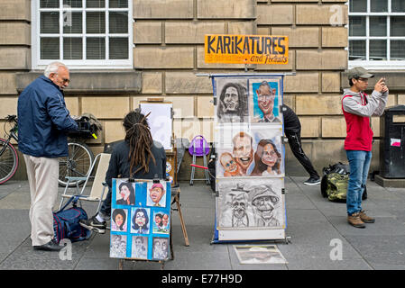 Un artista di strada con esempi del suo lavoro veli il suo commercio su High Street di Edimburgo. Foto Stock