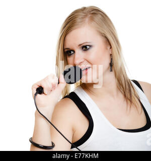 La musica. Ragazza bionda cantante pop musicista esecutore di cantare una canzone per un microfono isolato su bianco. Concerto. Foto Stock