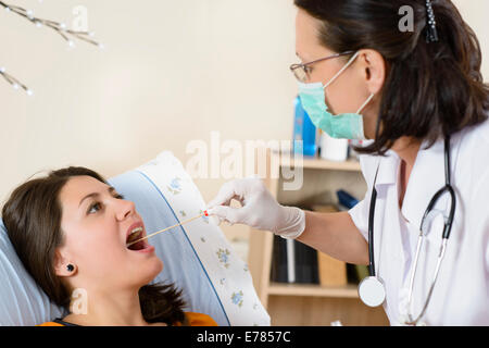 Giovane donna al medico che viene testato per il mal di gola Foto Stock