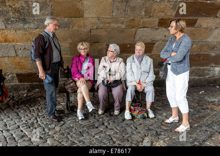 Stanco di persone anziane, turisti, relax, i pensionati sul banco sotto il Ponte Carlo, Praga, Repubblica Ceca Foto Stock