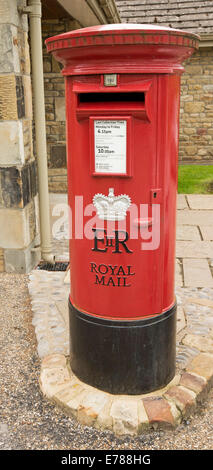 Tradizionale in rosso cassetta postale della British Royal Mail servizio postale sul marciapiede in villaggio inglese Foto Stock