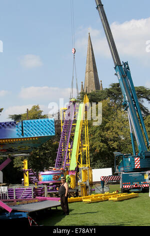 Witney, Oxfordshire, Regno Unito, 9 settembre 2014. Fiera dei lavoratori utilizzare una gru per impostare un rollercoaster ride in blazing sunshine in preparazione per la festa di Witney questo fine settimana. La festa annuale di Santa Maria è stato tenuto dal 1243 per commemorare il re-dedicazione della chiesa di Santa Maria quando il Vescovo ha dato un cervo al rettore di modo che la gente della città potrebbe festeggiare l'occasione. Oggi un arrosto di maiale sulla Chiesa ancora verde segna questa parte della tradizione accanto alle giostre e baracconi, chioschi, musica ed eventi sportivi Credito: Ric Mellis/Alamy Live News Foto Stock