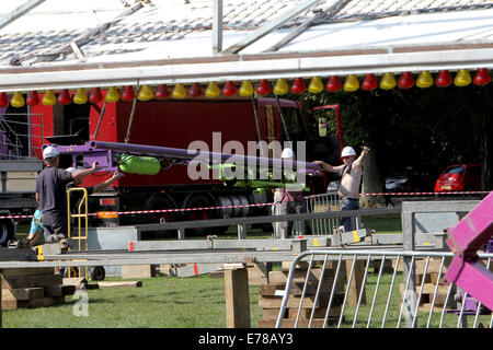 Witney, Oxfordshire, Regno Unito, 9 settembre 2014. Fiera dei lavoratori utilizzare una gru per impostare un rollercoaster ride in blazing sunshine in preparazione per la festa di Witney questo fine settimana. La festa annuale di Santa Maria è stato tenuto dal 1243 per commemorare il re-dedicazione della chiesa di Santa Maria quando il Vescovo ha dato un cervo al rettore di modo che la gente della città potrebbe festeggiare l'occasione. Oggi un arrosto di maiale sulla Chiesa ancora verde segna questa parte della tradizione accanto alle giostre e baracconi, chioschi, musica ed eventi sportivi Credito: Ric Mellis/Alamy Live News Foto Stock