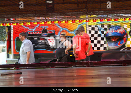 Witney, Oxfordshire, Regno Unito, 9 settembre 2014. Fiera dei lavoratori si prendono una pausa dalla impostazione di un dodgem ride in sole caldissimo in preparazione per la festa di Witney questo fine settimana. La festa annuale di Santa Maria è stato tenuto dal 1243 per commemorare il re-dedicazione della chiesa di Santa Maria quando il Vescovo ha dato un cervo al rettore di modo che la gente della città potrebbe festeggiare l'occasione. Oggi un arrosto di maiale sulla Chiesa ancora verde segna questa parte della tradizione accanto alle giostre e baracconi, chioschi, musica ed eventi sportivi Credito: Ric Mellis/Alamy Live News Foto Stock