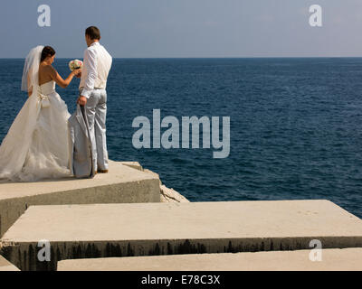 Sposa e lo sposo in piedi sulle rocce vicino al mare Foto Stock