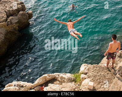 I ragazzi che si tuffano da scogliere nel mare blu di Nizza, Francia Foto Stock