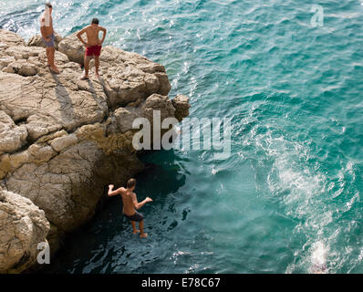 I ragazzi che si tuffano da scogliere nel mare blu di Nizza, Francia Foto Stock