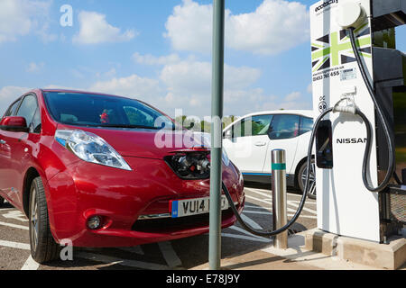 La Nissan Leaf auto elettrica essendo caricato nel Parcheggio Servizi Corley Warwickshire, Regno Unito Foto Stock