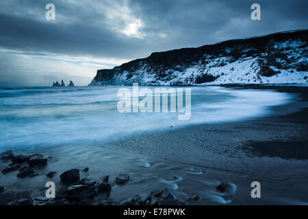 La spiaggia di sabbia nera a Vík í Mýrdal in inverno, con il basalto Renisdrangar mare pile al di là, sud dell'Islanda Foto Stock