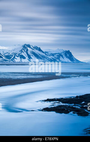 La figura solitaria di Wendy sulla costa a Budir con montagne di Holsfjall e Penisola Snaefellsnes , western Islanda Foto Stock