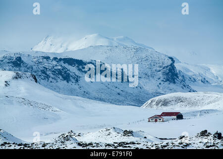 Un agriturismo isolato nella neve con la massa di Katla oltre, sud dell'Islanda Foto Stock