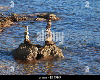Pila di pietre rotonde su una riva del mare Foto Stock