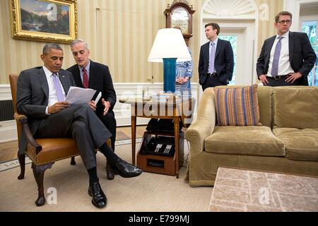 Il Presidente Usa Barack Obama conferisce con il capo del personale Denis McDonough prima di fornire dichiarazioni alla stampa con il Primo Ministro Tony Abbott di Australia nell'Ufficio Ovale della Casa Bianca Giugno 12, 2014 a Washington, DC. In piedi a destra sono: Jennifer Palmieri, direttore delle comunicazioni; Principal Vice segretario stampa Josh serio; e premere il Segretario Jay Carney. Foto Stock