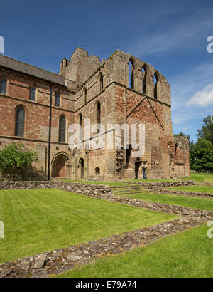 Ampia red ruderi di pietra del centro storico di Lanercost Priory con erba di smeraldo e il blu del cielo Foto Stock