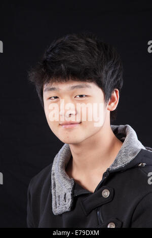 Uomo asiatico in una camicia, seduto e guardando la telecamera con un sorriso Foto Stock