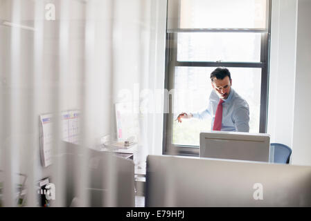 Un uomo in piedi su una scrivania guardando lo schermo di un computer. Foto Stock