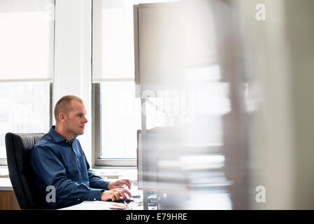 Un uomo che lavora in un ufficio a una scrivania utilizzando un mouse del computer. Incentrato su un'attività. Foto Stock