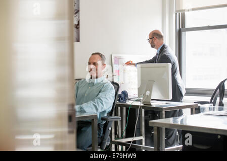 Vita in ufficio. Due persone seduto alla scrivania con computer. Foto Stock