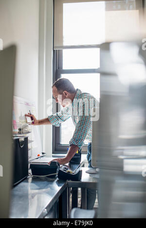 Vita in ufficio. Un uomo in piedi fino a lavorare e a rendere note su un tabellone a parete. Gestione di progetto. Foto Stock