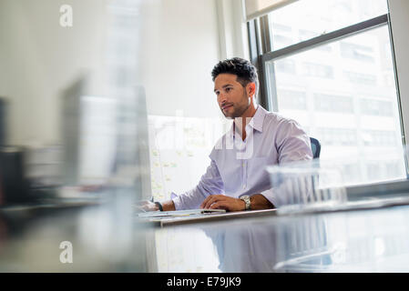 Vita in ufficio. Un uomo che lavora da solo in un ufficio. Foto Stock