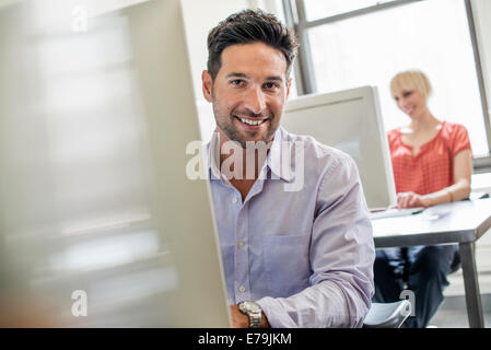 Vita in ufficio. Due persone seduto alla scrivania con computer. Foto Stock