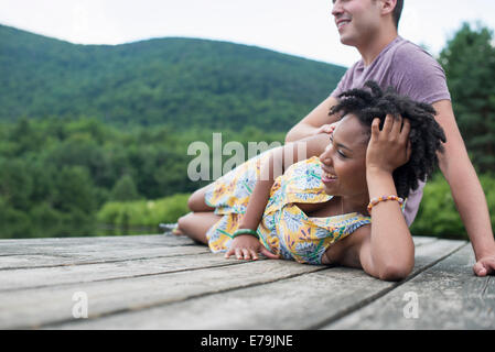 Un paio di relax su un molo che si affaccia su un lago di montagna. Foto Stock