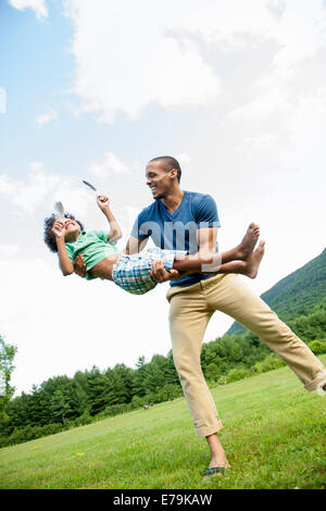 Un uomo sollevando il suo figlio tra le braccia la riproduzione all'esterno. Foto Stock