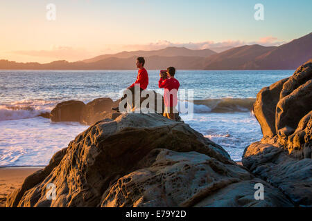 Due amici che si diverte a scattare foto su Baker Beach nella Baia di San Francisco Foto Stock