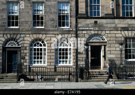 Uomo che cammina passato edifici georgiani nella zona nuova di Edinburgo Foto Stock