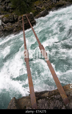 Due rotaie arrugginito del ponte danneggiato sulla montagna fiume tumultuoso Foto Stock