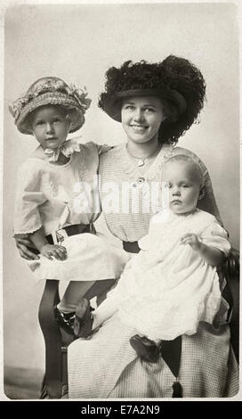 Donna con cappello scuro seduto con due bambini, uno con Hat, Ritratto, circa 1915 Foto Stock