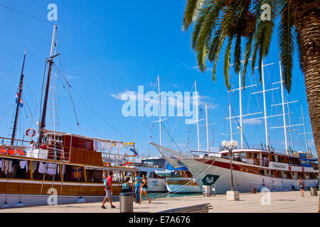 Vista del lungomare di Trogir, turisti passeggiate e crociera le barche sono ormeggiate lungo la passeggiata pronto per il prossimo tour di crociera Foto Stock