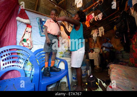 Medicazione di donna a suo figlio di 7 anni, per il suo primo giorno di scuola, campo Icare per rifugiati di terremoto, Fort National, Port-au-Prince Foto Stock