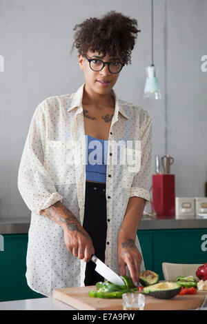 Ritratto di giovane donna tagliare le verdure in cucina Foto Stock
