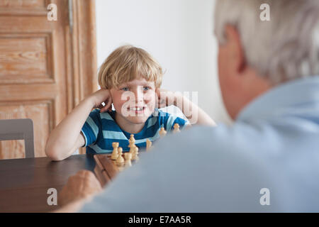 Nipote di felici giocando a scacchi con il nonno a casa Foto Stock