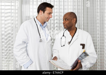 Due medici in camice da laboratorio consultazione su un fascicolo medico Foto Stock