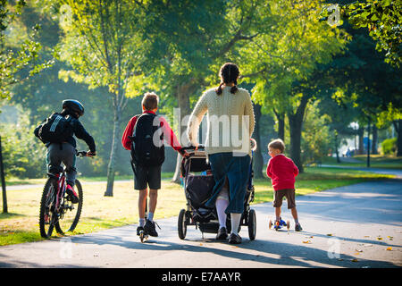 Su un soleggiato fine autunno mattina con il sole dappling attraverso gli alberi, i genitori e i bambini testa per la scuola primaria verso il basso Plascrug Avenue in Aberystwyth Wales UK. "L'estate indiana' delle belle risolte secco e caldo è previsto di continuare a Ben nella prossima settimana Photo credit: Keith Morris/Alamy Live News Foto Stock