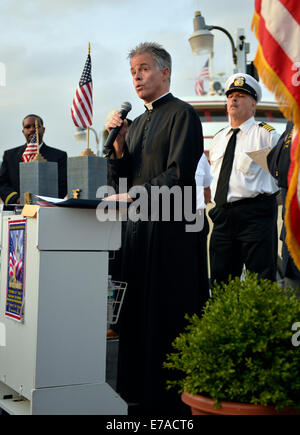 Freeport, New York, Stati Uniti d'America. Decimo sett. 2014. Un pastore dà la benedizione a dockside cerimonia di commemorazione in onore delle vittime degli attacchi terroristici dell'11 settembre 2001, alla barca Miss Freeport V, su Freeport il miglio nautico. Inoltre le cerimonie sono state detenute a bordo della nave che ha navigato dal Woodcleft Canal sulla riva sud di Long Island, alla vigilia del tredicesimo anniversario degli attacchi dell'11 settembre. Credito: Ann e Parry/Alamy Live News Foto Stock