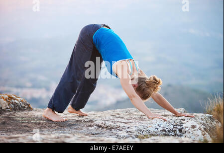 Giovane donna caucasica eseguendo il cane verso il basso lo yoga pone all'aperto Foto Stock