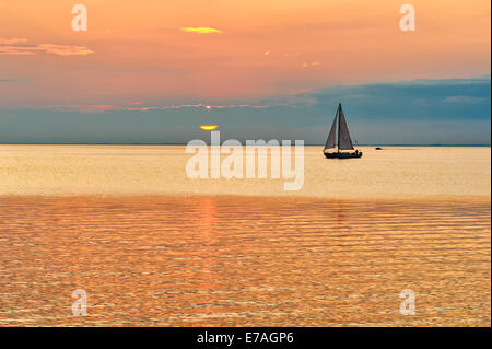 Silhouette di una barca a vela su acque calme, contrastando un arancio e blu Cielo di tramonto sulla regione dei Grandi Laghi, Green Bay, il lago Michigan nel Wisconsin, USA. Foto Stock