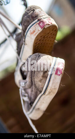 Coppia di vecchi formatori appesi da linee di alimentazione, calzatura Tossing. Foto Stock