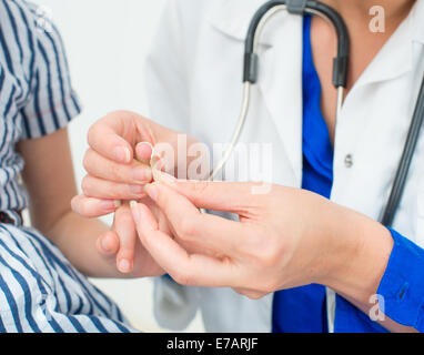 Medico mette bendaggio adesivo sul dito del bambino. Foto Stock